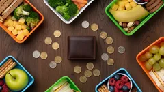 Alimentos saludables en envases plásticos y billetera con monedas sobre mesa de madera.