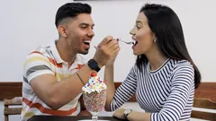 Pareja sonriente a punto de darse de comer mutuamente